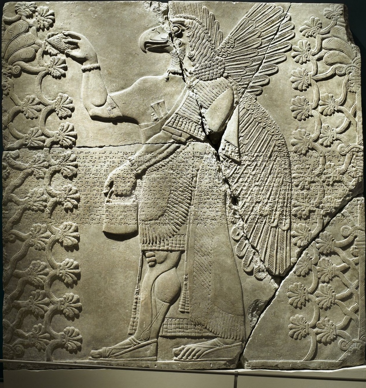 Eagle-headed winged genie standing between two sacred trees — Assyrian relief, c. 883–859 BCE